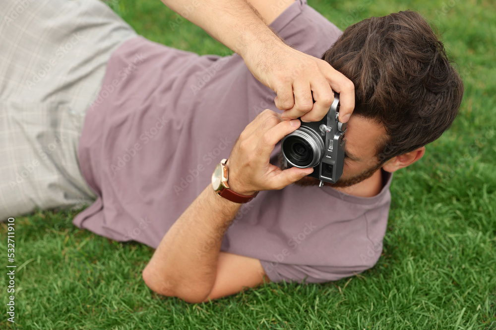 Man with camera taking photo on green grass. Interesting hobby Man with camera taking photo on green grass. Interesting hobby