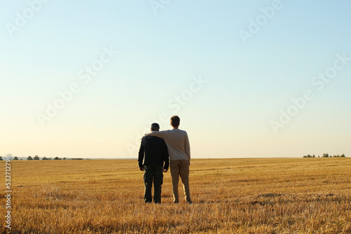Young adult son and father in the autumn meadow on a blue sky background. Pavel Kubarkov, i and my Father Alexander. Photo was taken 10 September 2022 year, MSK time in Russia.