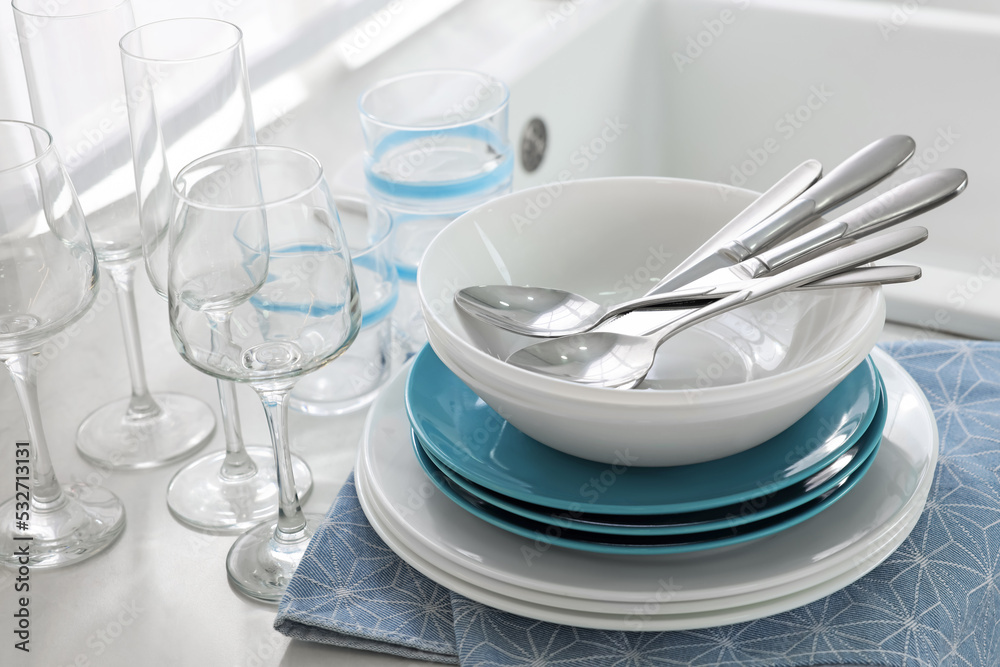 Different clean dishware, cutlery and glasses on countertop, closeup