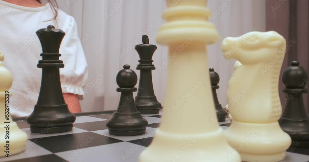Girl plays chess. Chess figures extreme closeup Girl plays chess. Chess figures extreme closeup