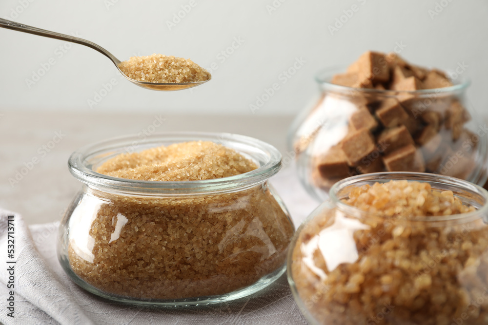 Taking spoon of brown sugar from glass bowl on table Taking spoon of brown sugar from glass bowl on table
