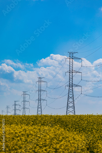 rural landscape with a voltage power lines against a blue cloudy sky