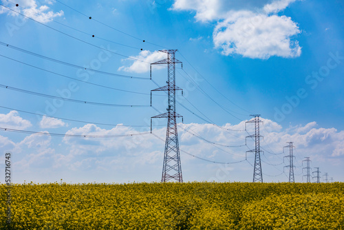 rural landscape with a voltage power lines against a blue cloudy sky