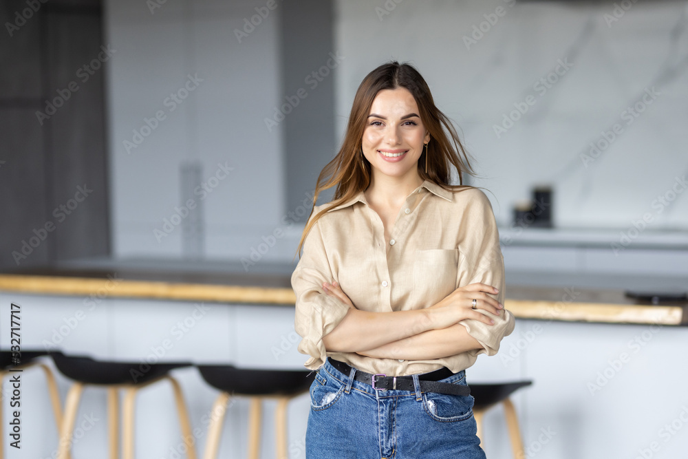 Young pretty woman standing near desk in the kitchen .