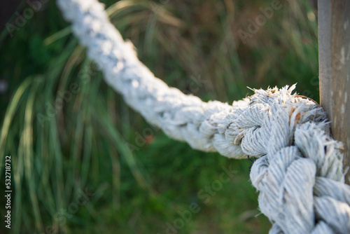 Absperrung aus einem weißen Tau mit Knoten in der Natur gespannt photo