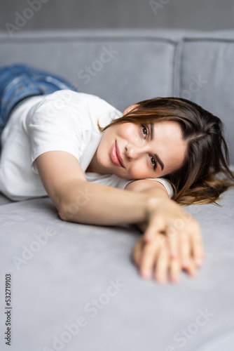 Tired young woman lying on cozy couch take nap daydreaming in living room