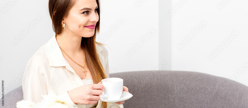 Female caucasian client with a cup of coffee in his hands smiling at a doctor's appointment Female caucasian client with a cup of coffee in his hands smiling at a doctor's appointment