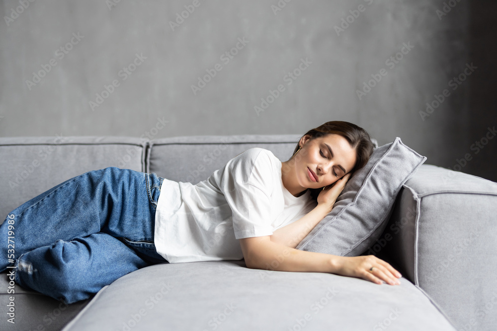 Young sleepy woman falls down on sofa. Apathetic tired lazy lady sleeping on couch at home.