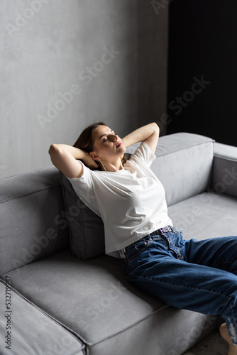 Relaxed peaceful woman relaxing on cozy couch in living room, satisfied young female with hands behind head leaning back on sofa © F8  \ Suport Ukraine