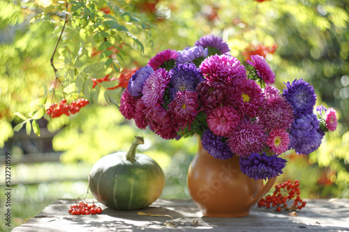 A bouquet of colorful asters on the table in the autumn sunny garden. photo