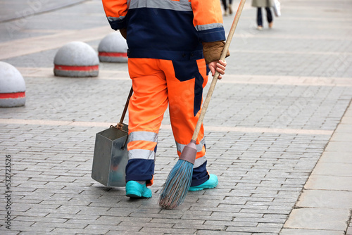 Janitor woman with broom and scoop on a autumn street. Cleaning the city, street sweeper on people background