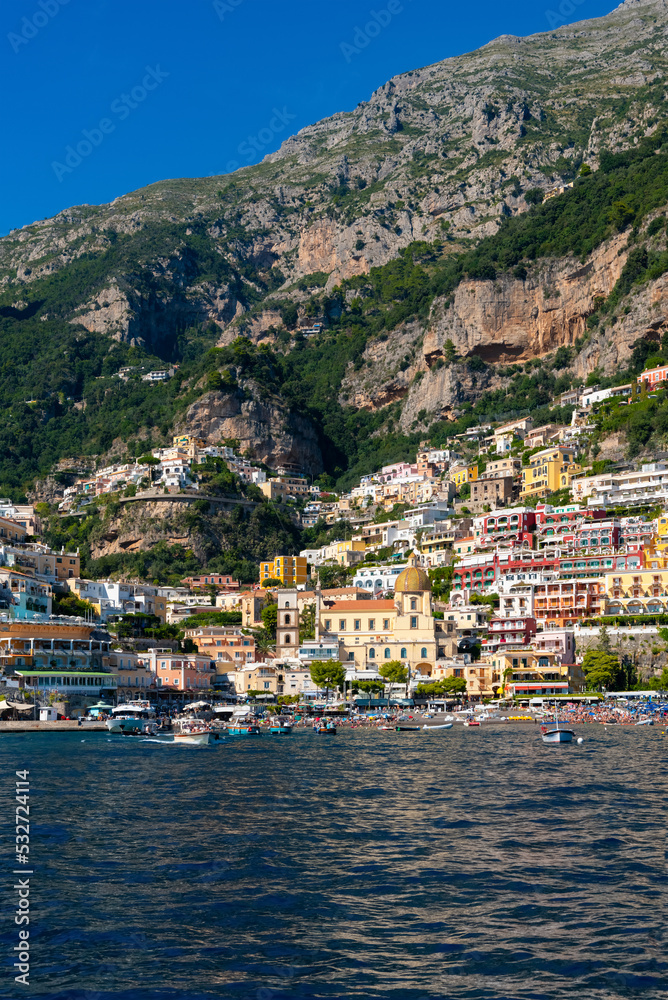 Positano on the famous Amalfi Coast in Campania Italy. Picturesque historic village in world heritage area with colorful houses built on the coastline. Harbour and beech seen from a tourist ferry.