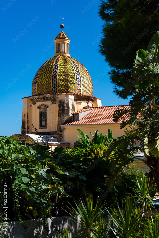 Church of „St Maria Assunta“ in Positano on the famous Amalfi Coast in Campania Italy. Colorful cupola is a monument in the picturesque historic village. World heritage site is a popular tourist spot.