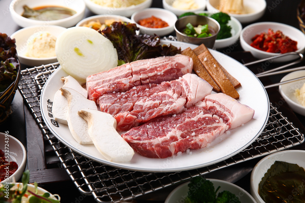Korean table setting with grilled pork golden brown on the grill and side dishes set 그릴 위 노릇노릇하게 돼지고기를 굽고 있고 반찬이 세팅되어 있는 한상차림 Korean table setting with grilled pork golden brown on the grill and side dishes set 그릴 위 노릇노릇하게 돼지고기를 굽고 있고 반찬이 세팅되어 있는 한상차림