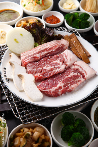 Korean table setting with grilled pork golden brown on the grill and side dishes set 그릴 위 노릇노릇하게 돼지고기를 굽고 있고 반찬이 세팅되어 있는 한상차림