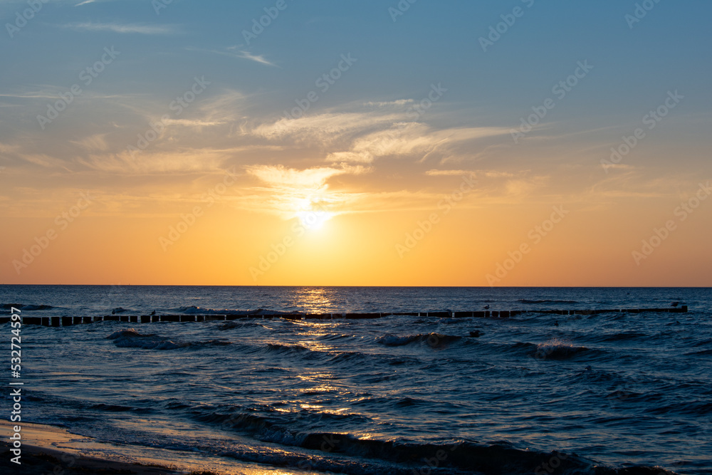Sunset over the sea, with groynes in the water
