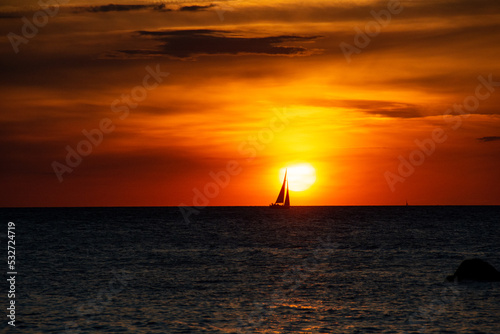 Sunset over the sea with a sailing ship on the horizon