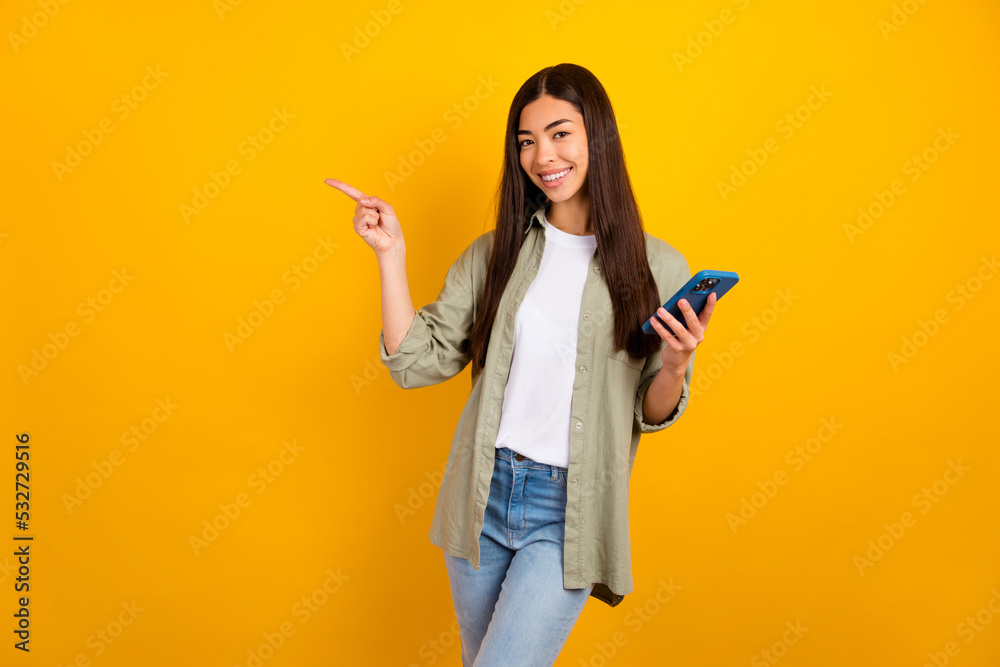 Photo of young adorable female promote recommend new modern technology phone isolated on yellow color background Photo of young adorable female promote recommend new modern technology phone isolated on yellow color background