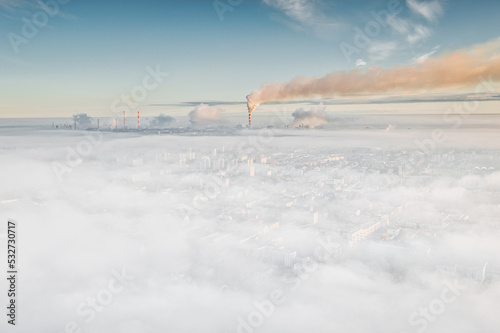 Foggy morning skyline view of downtown Płock with steaming refineries and industrial facilities in background. Exhaust smoke / Air pollution photo