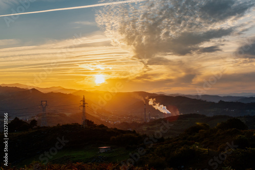mountainous landscape with thermal power plant emitting steam and fumes at sunset. Industry and sustainability