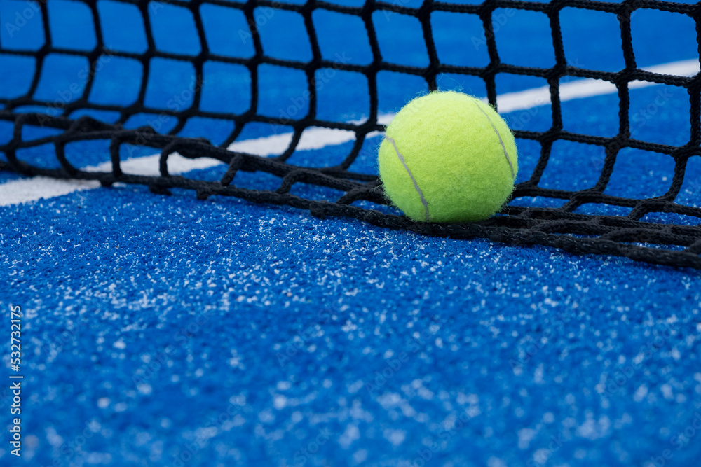 selective focus, a ball at the net on a blue paddle tennis court