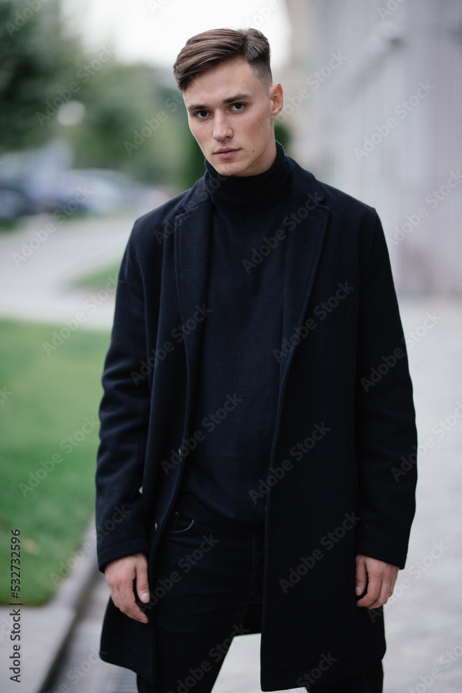 Fashion portrait of a young guy in black clothes of model appearance on the street among skyscrapers and alleys Fashion portrait of a young guy in black clothes of model appearance on the street among skyscrapers and alleys