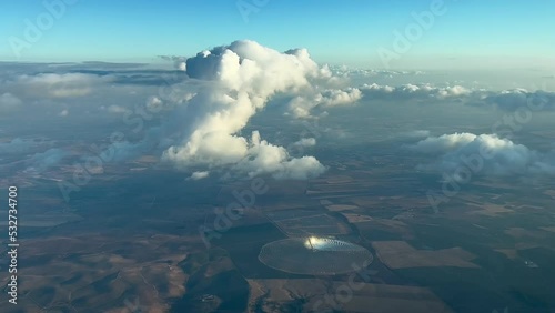 Nice view from a jet cockpit of a tiny cumulus ahead overflying a rounded solar farm in Andalucia, Spain. 10000 metres high. Pilot point of view. photo