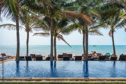 Swimming pool with palm tree and lounge on the beach in tropical sea © Mumemories