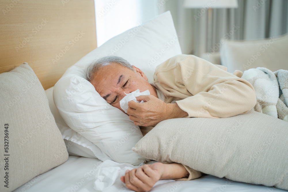Senior man sneezing due to discomfort while lying in bed at home,Healthcare,Flu,Hygiene and people concept. Senior man sneezing due to discomfort while lying in bed at home,Healthcare,Flu,Hygiene and people concept.