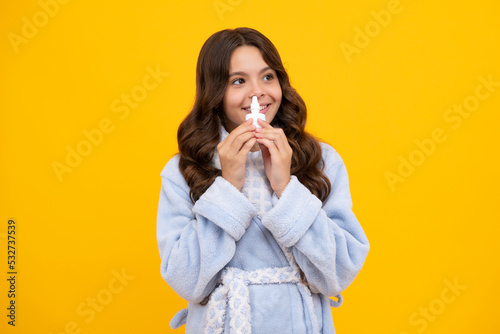 Girl hold medicine nasal spray from running nose, virus pandemic. Sick teen girl with nasal spray on yellow background.