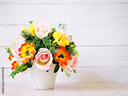 Pastel colored artificial flowers bouquet in pot on table, copy space for text or lettering pretty background or wallpaper ,mother's day ,still life ,women's day festive background ,colorful elegant 