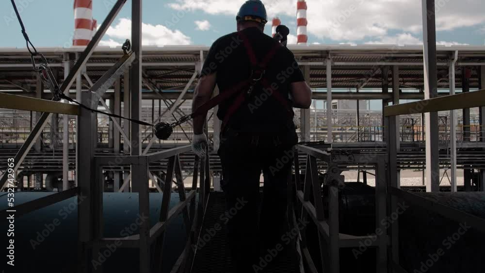 Professional assembler heightsman in helmet and safety system goes out on a tank car to load fuel for transportation Professional assembler heightsman in helmet and safety system goes out on a tank car to load fuel for transportation