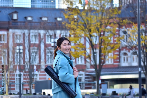 アジャスターケースを担ぎ東京駅を歩くビジネスウーマン © photo pocket