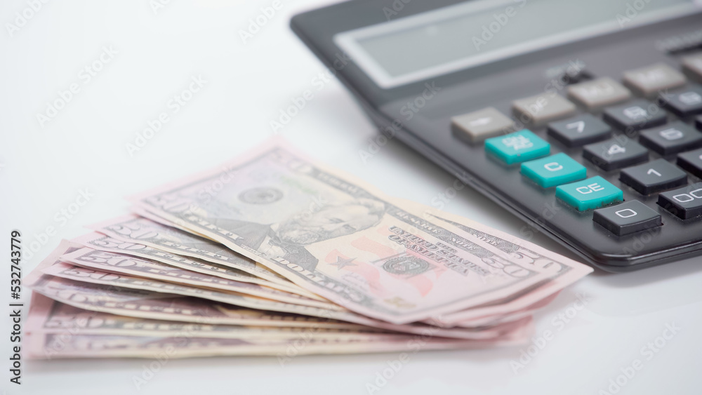dollar banknotes near blurred calculator on white background. dollar banknotes near blurred calculator on white background.