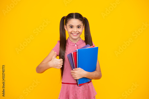 Teen girl pupil hold books, notebooks, isolated on yellow background, copy space. Back to school, teenage lifestyle, education and knowledge. Happy teenager, positive and smiling schoolgirl.