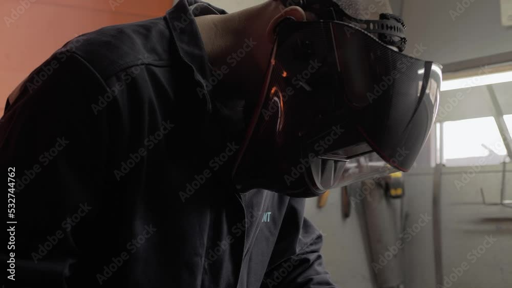 Modern welder puts on a technological helmet and starts welding parts. Close-up Modern welder puts on a technological helmet and starts welding parts. Close-up