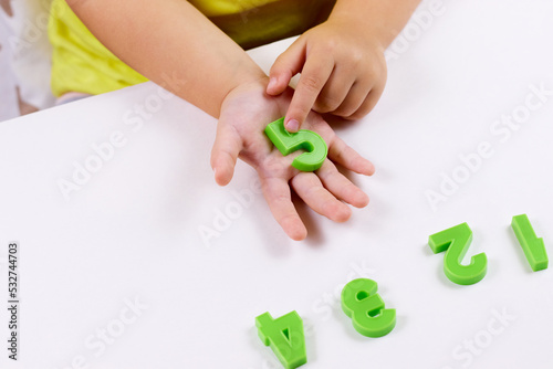 The child shows the number 5. Early development, playing with numbers, learning to count. selective focus