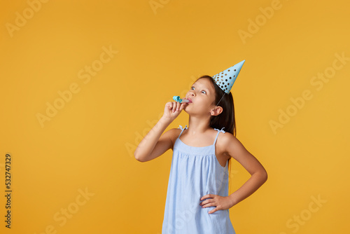 happy little birthday girl with party cone hat and whistle