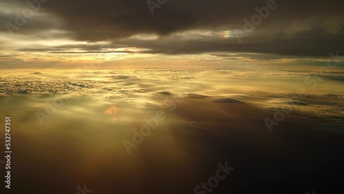 夕日に染まる日没直前の雲上を飛ぶ飛行機からの幻想的な光の風景
