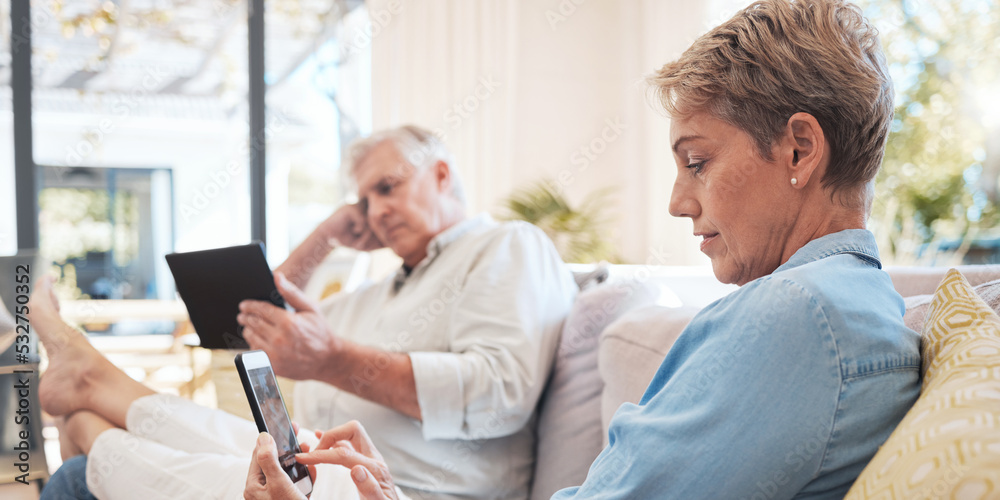Obraz premium Relax senior couple on sofa with smartphone and tablet technology to watch film while networking on social media with home wifi. Elderly woman and man on couch with digital or online internet content