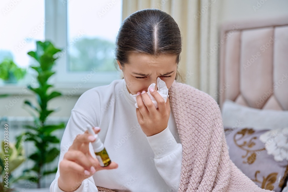 Teenage girl with runny nose treating rhinitis using nose drops spray Teenage girl with runny nose treating rhinitis using nose drops spray