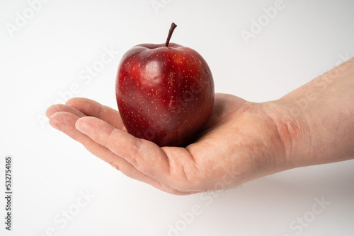 Male hand holding a red apple on a white background