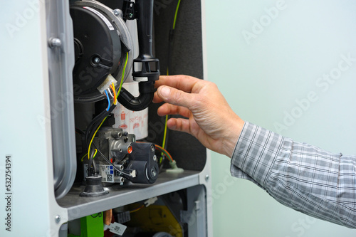 Man hand working with a gas condensing boiler disassembled, parts of section gas condenser