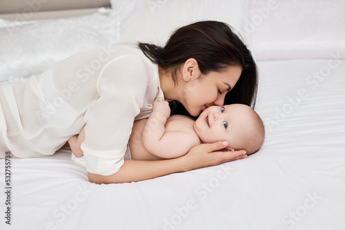 mother plays with her baby girl in the bedroom.