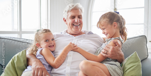 Happy family  retirement and old man playing with children on the sofa bonding  happiness and laughing together. Smile  elderly and grandpa with little girls enjoying quality time on a couch at home