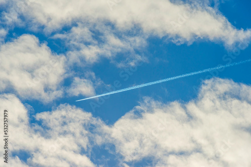Airplane flying into a blue cloudy sky in bright sunlight in autumn, Almere, Flevoland, The Netherlands, September, 2022
