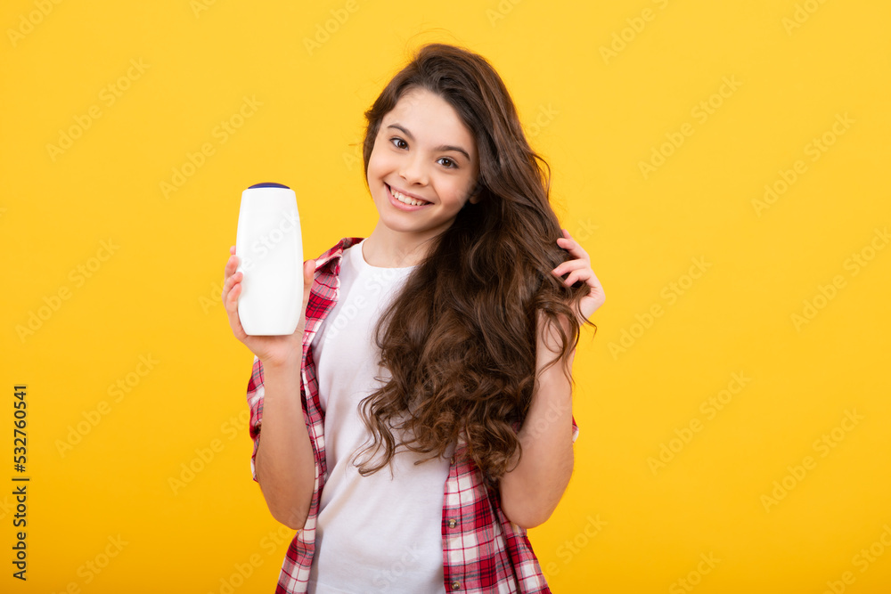 Teenager child girl showing bottle shampoo conditioners or shower gel. Hair cosmetic product. Bottle for advertising mock up copy space. Happy teenager, positive and smiling emotions of teen girl. Teenager child girl showing bottle shampoo conditioners or shower gel. Hair cosmetic product. Bottle for advertising mock up copy space. Happy teenager, positive and smiling emotions of teen girl.