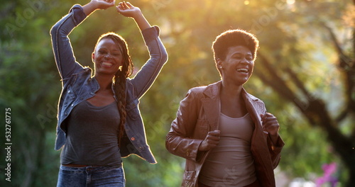 Two women celebrating news outside dancing. African black ethncity friends dance photo