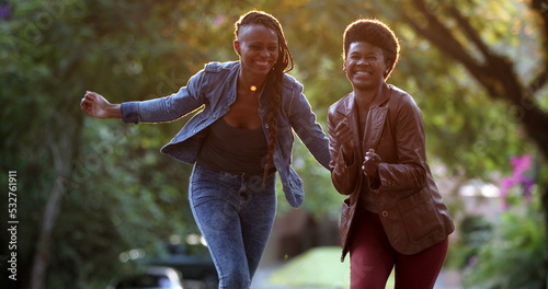 Two women celebrating news outside dancing. African black ethncity friends dance photo