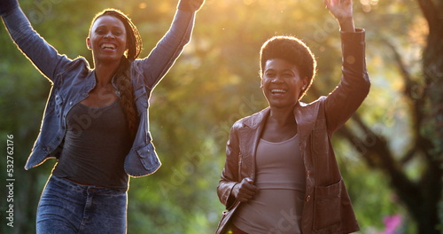 Two women celebrating news outside dancing. African black ethncity friends dance photo
